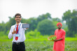 © PRASANNAPIX - Young indian agronomist showing smart phone with farmer at green chilly field