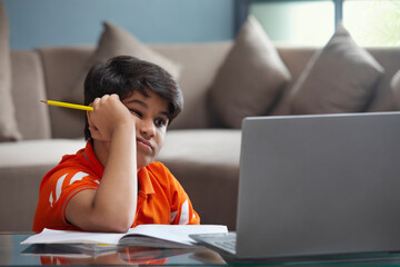 A YOUNG BOY TRYING TO CONCENTRATE DURING ONLINE CLASS	