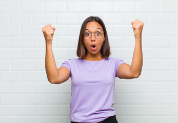 latin woman celebrating an unbelievable success like a winner, looking excited and happy saying take that!