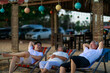 © sutthichai - Happy Asian family enjoy talking together on the sunbed on the beach side restaurant.