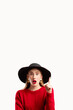 © golubovy - Omg face. Sale discount. Fashion look. Personal offer. Information banner. Shocked woman in red sweater black hat pointing up on copy space isolated on white.