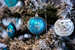 Christmas background. Detail view of blue and silver baubles and festive decorations hanging on a white christmas tree.