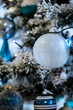 Christmas background. Detail view of blue and silver baubles and festive decorations hanging on a white christmas tree.