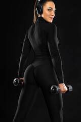 Wall Mural - Athlete with dumbbells make fitness exercises on black background. Sporty fit woman in sport concept.