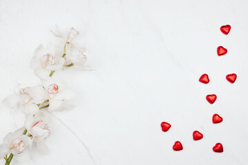 Sticker - Valentine's white orchids with red chocolate hearts on a white marble background