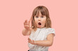 Little blonde girl points a no forbidden gesture, palm to the camera. Pink isolated background.