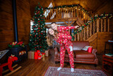 Fototapeta Młodzieżowe - A young mother and son playing near the Christmas tree. Family in red Christmas pajamas. Christmas homeliness. Holidays and New Year's gifts