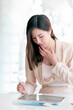 © NAMPIX - Portrait of young asian woman working on tablet while sitting at her desk in modern office.
