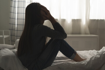 Suffer from depression , mental health problem. asian young woman sitting on the bed feeling depressed.