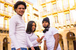© unai - Lifestyle, black Latino friends having fun on the street with the phone. Afro-haired boy, young brunette girl and brunette brunette with long hair wearing a hat