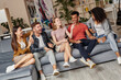 © Kostiantyn - Joyful moments. Young beautiful girl telling something to her best friends, making them laugh while sitting together on the couch at home. Happy multicultural people relaxing together indoors
