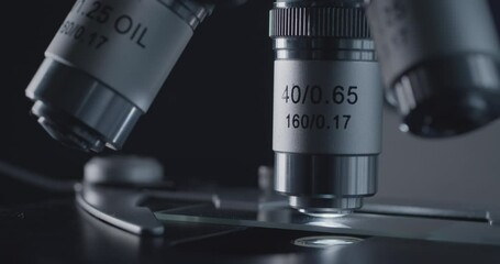 Wall Mural - close-up shot of sample slide and microscope with metal lens at laboratory.