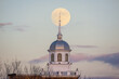 Full moon rising behind a beautiful building with a white steeple. Garden City, New York