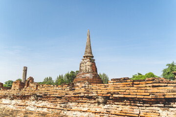 An ancient pagoda in an old temple and a very old brick wall in Ayutthaya, Thailand.