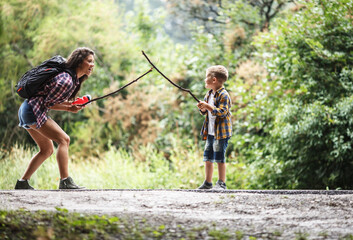 Wall Mural - mother and her little sons hiking trough forest .making fun and fight with wooden sticks.