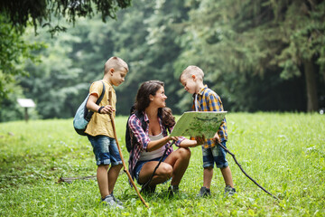 Wall Mural - mother and her little sons hiking . they're taking a break and examining the map.