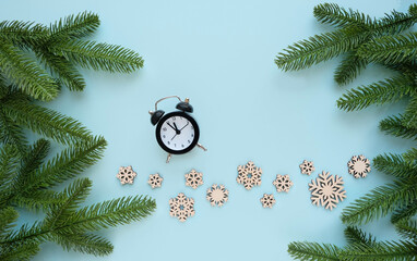 Christmas and new year concept. alarm clock, snowflakes and Christmas fir branches on blue background. winter time concept, new year symbol. flat lay. copy space