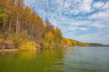 Canvas Print - Autumn forest trees are reflected in the river water of the panoramic landscape. Blue sky with clouds.