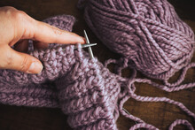 An Adult Woman Holds Knitting Needles In Her Hands. Pale Lilac Thread Color.