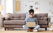 Joyful Relaxed Ethnic Woman Using Laptop With Interest At Home.