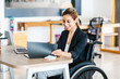 © Marcos - Disabled Hispanic female sitting at office desk, working on laptop in Mexico City