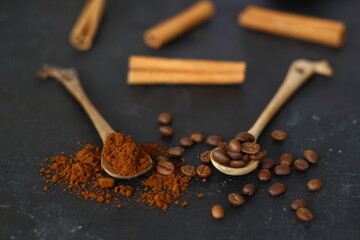 two spoons with coffee on a black background. One spoon with coffee beans. Second spoon with ground coffee. nearby lies coffee bean