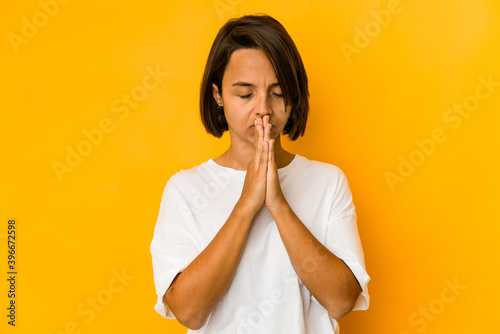Fotografía Young hispanic woman isolated on yellow praying, showing devotion, religious person looking for divine inspiration