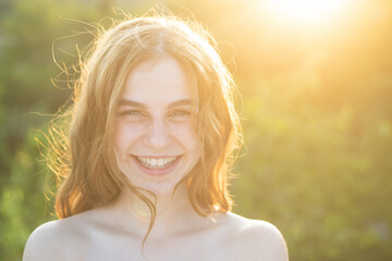 beautiful smiling teenage girl in blue blouse, against green of summer park. beauty joyful teen girl