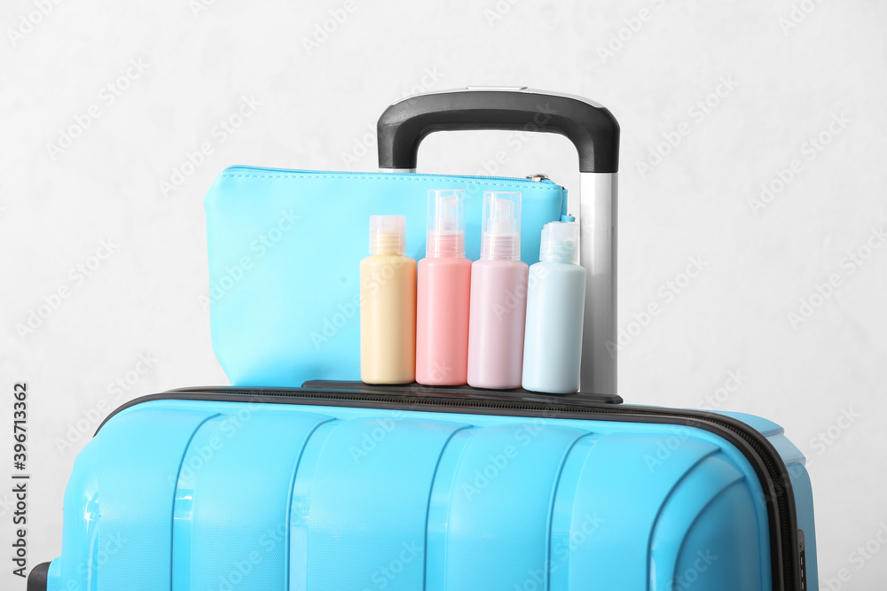 Travel cosmetics kit and packed suitcase on white background