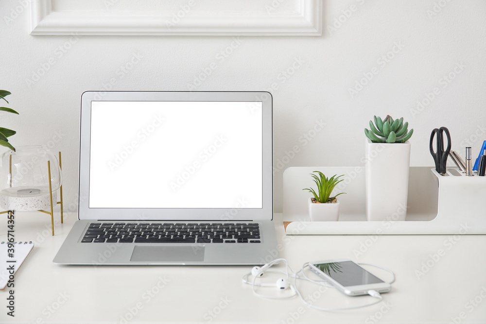 Stylish workplace with laptop near white wall