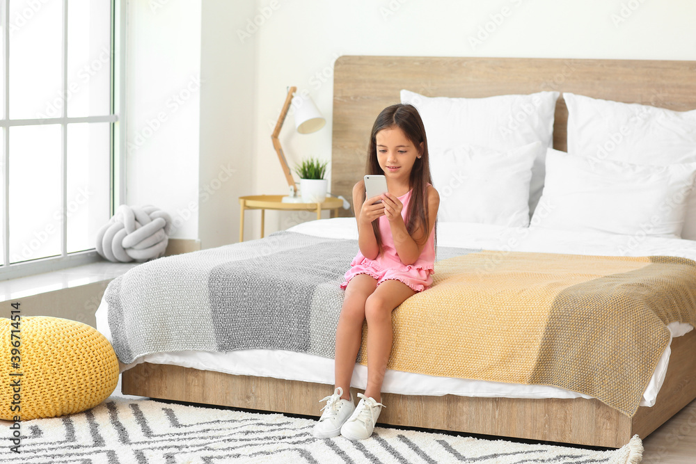 Cute little girl with mobile phone in bedroom Stock Photo | Adobe Stock