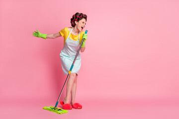 Sticker - Full length body size view of nice ecstatic cheerful housemaid singing hit song using besom like mic isolated pink color background