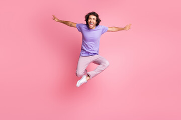 Wall Mural - Full size photo of joyful funky guy jump up make hands wings wear pink pants purple t-shirt isolated on bright pink color background