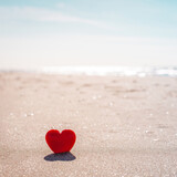Fototapeta Uliczki - Romantic symbol of red heart on the sand beach
