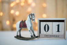Cube Wooden Calendar Showing Date On 1th December With Old Toy Rocking Horse Over Bokeh Background. Advent Calendar, Christmas Background, Copy Space