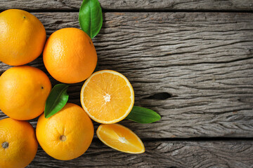 fresh orange fruits with leaves on wooden table.