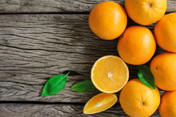 fresh orange fruits with leaves on wooden table.