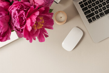 Wall Mural - Laptop, beautiful pink peony tulip flowers bouquet on beige table background. Flat lay, top view minimalist home office desk workspace.