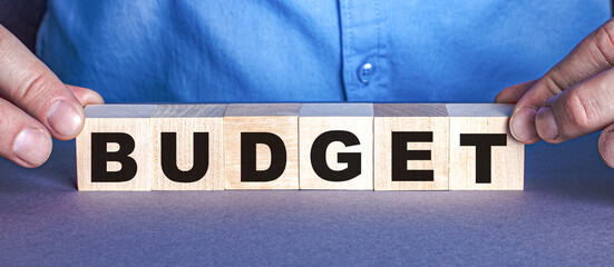 The word BUDGET is made up of wooden cubes by a man. Business concept