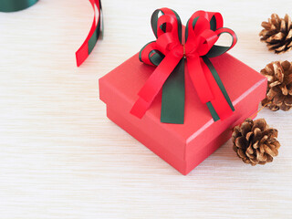 Red gift box with a bow and golden pine cone, ribbon on white fabric with copy space. Concepts for holiday. Christmas background..