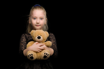 Wall Mural - Little girl with a teddy bear on a black background.