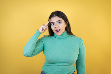 Young caucasian woman over isolated yellow background smiling and thinking with her fingers on her head that she has an idea.