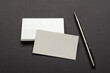 © uaPieceofCake - Closeup of metalic pen, stack of empty business cards on the dark grey surface