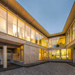 View of the two legs of a sustainable wood office building from the inner courtyard with lighting at night