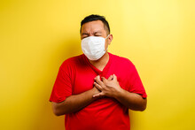 Asian Guy Wearing Mask Feeling Pain In His Chest, Gesture Holding Left Chest