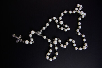 White rosary on black background, view from above