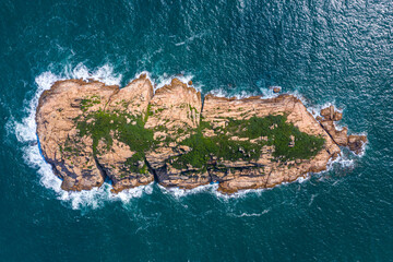 Aerial view of tiny rocky island in sea