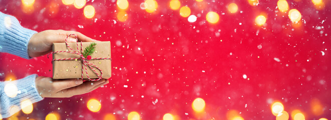 Wall Mural - woman hands giving rustic present with snowing and lights