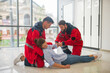 © zinkevych - Two medical workers in red uniform halping a faint woman