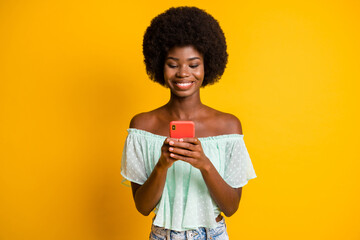 Sticker - Photo portrait of girl holding phone in two hands texting isolated on vivid yellow colored background